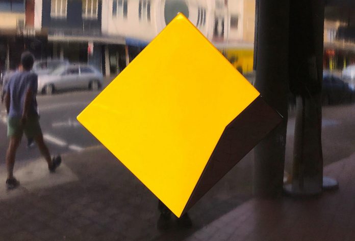 FILE PHOTO - A pedestrian walks past a logo for the Commonwealth Bank located outside a branch in Sydney, Australia